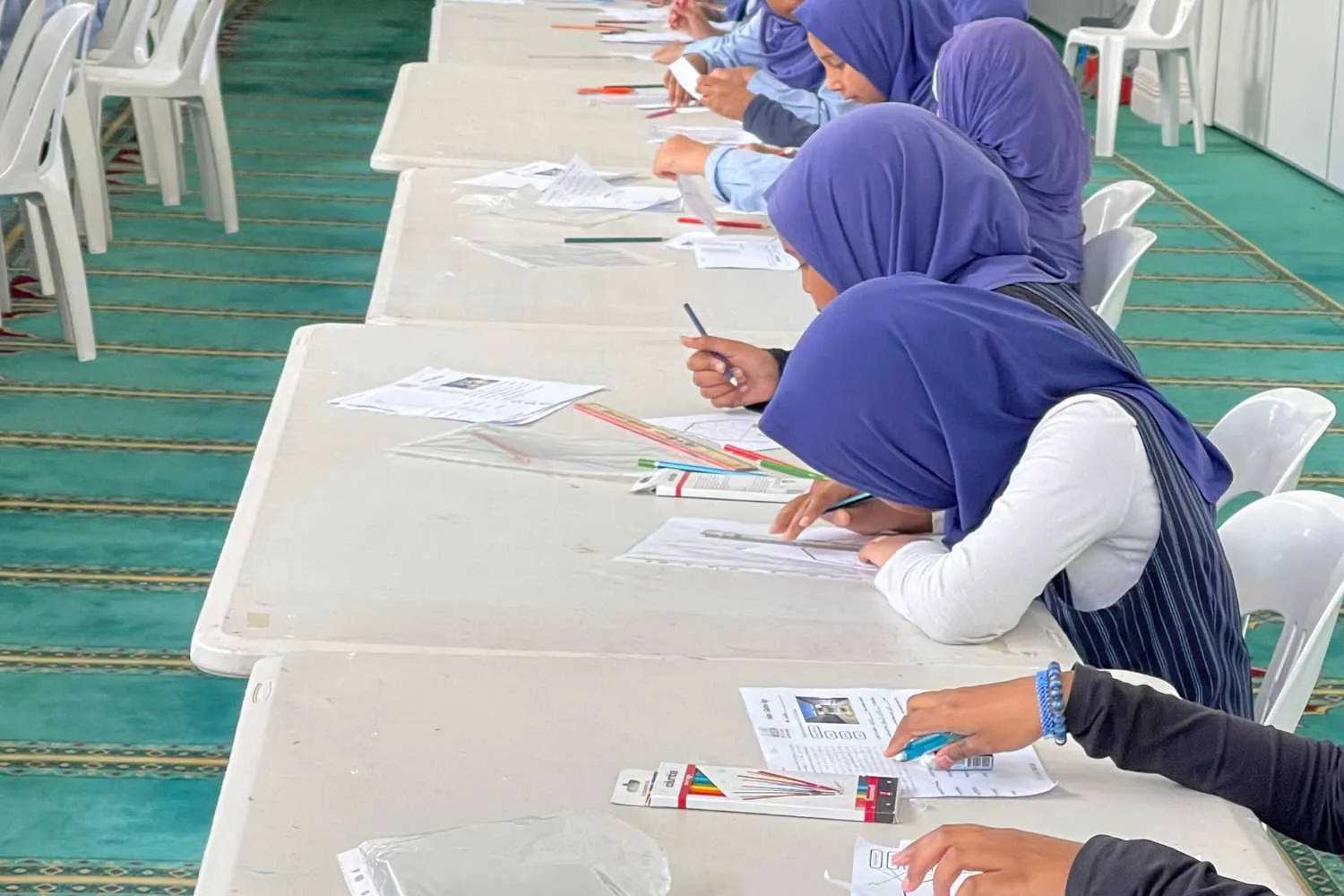 Students filling in worksheets at long tables
