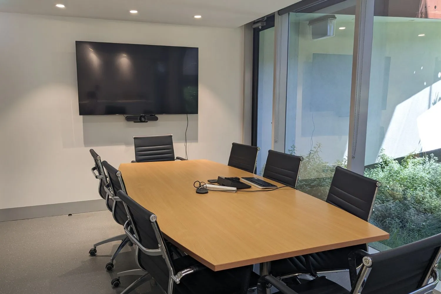 The board room with a long timber table and wall screen